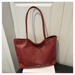 Détail de la texture en cuir tressé rouge foncé et étiquette de mode sur le cabas