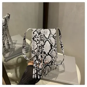 Detail of snake skin pattern square bag with long fringe tassels and metal buckle strap
