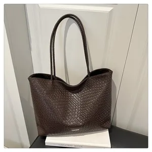 Détail macro de la texture tressée marron foncé sur le sac cabas avec logo métal