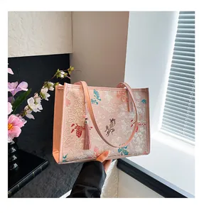 Detail of pink embroidered tote bag with traditional patterns and decorative tassels
