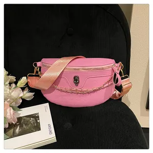 Detailed close-up of pink leather crossbody bag with skull embossing and gold chain strap