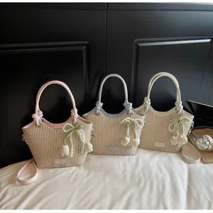 Detalle de bolsos tipo cubo de paja tejida en rosa, azul y beige con colgantes de perlas