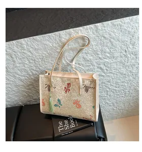 Detail of beige tote bag featuring embroidered traditional clouds and goldfish patterns