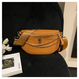 Detailed view of caramel chest bag with embossed skull pattern and metallic chain link