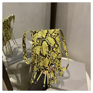 Detail of neon yellow snake skin crossbody bag with long fringes and silver buckle