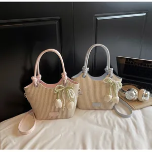 Detalle de bolsos cubo de paja con cadenas de perlas y colgantes de tulipán en escena