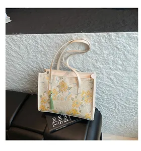 Detailed view of floral embroidery and green tassel on a cream jacquard tote bag