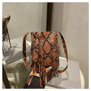 Close-up of orange snake print leather bag featuring long fringe tassels and silver buckle