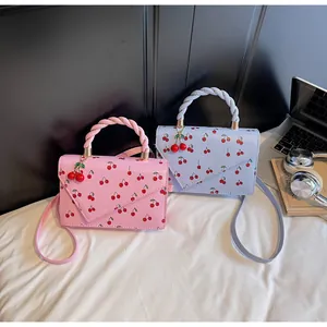 Détail de sacs bandoulière à imprimé cerise avec poignées tressées et charmes cerises