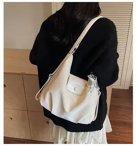 Rear view of a model wearing a soft beige square bag with silver butterfly pendant