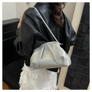Silver woven shell bag with pleated texture shown on shoulder with black leather jacket