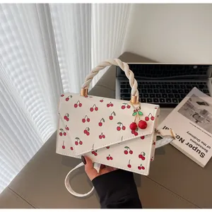 Détail du sac carré blanc à motif cerise avec anse corde et pendentif cerise