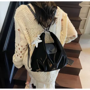 Detail of black glossy backpack with silver star charm and decorative pleats on a model