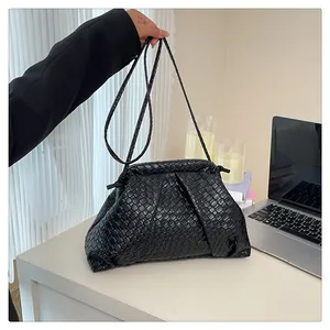 Detail of black woven checkerboard shell bag with soft pleated cloud texture and strap