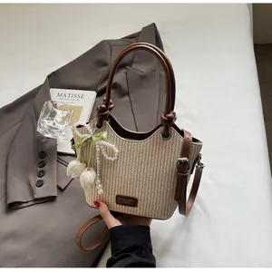 Detalle del bolso de paja tejida con asas de cuero y colgante de perlas y tulipán