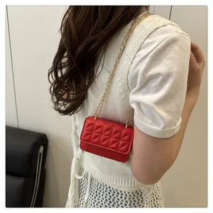Detailed view of red quilted mini bag with gold chain strap worn by a model