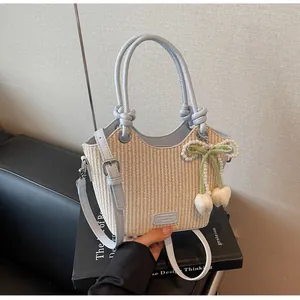 Detalle del bolso de paja tipo cubo con ribete de cuero azul claro y colgante de tulipa