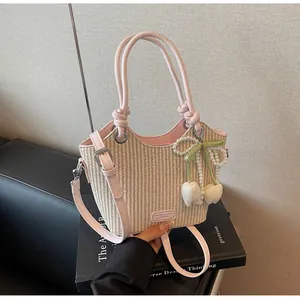 Detalle de bolso saco de paja con ribete de cuero rosa y colgante de perla y lazo