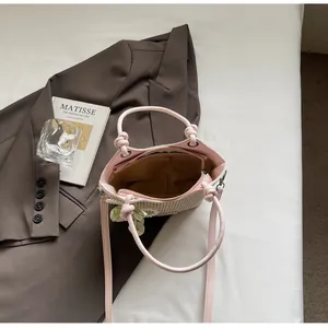Detalle de un bolso cubo de paja trenzada con ribetes rosas y colgantes de perlas