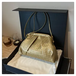 Detailed macro shot of golden woven texture on a minimalist shell shoulder bag