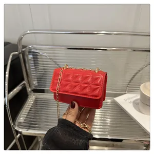 Detailed view of red quilted PU leather flap bag with gold chain strap held by hand