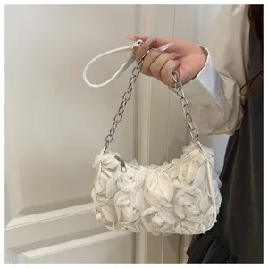 Detailed close-up of white 3D floral petals and silver chain on an elegant handbag