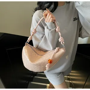 Detail of pink woven leather crescent bag with knot handle and amber bead charm