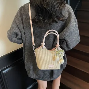 Bolso cubo de paja beige con ribete de cuero rosa y colgante floral de verano