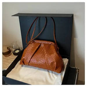 Detail of caramel woven shell bag inside a luxury gift box with fine texture