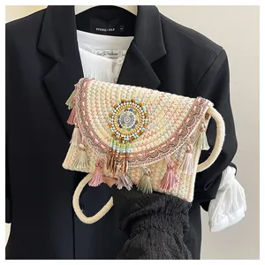 Dettaglio della borsa in paglia boho con nappe colorate e ricami di perline