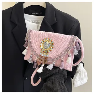 Dettaglio borsa di paglia rosa con frange viola e ornamento mandala di perline ricamate