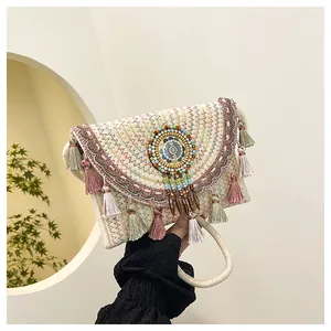 Dettaglio borsa bohémien in paglia con ricami colorati e nappe sfrangiate in colori pastello