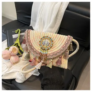 Dettaglio borsa in paglia intrecciata con perline colorate, nappe e ricami etnici