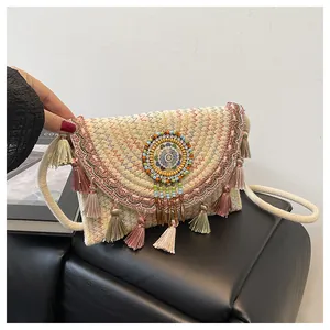 Dettaglio borsa in paglia bohémien con nappe colorate e motivi mandala ricamati