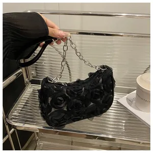 Détail du sac sous le bras en maille noire avec roses 3D et chaîne en métal argenté