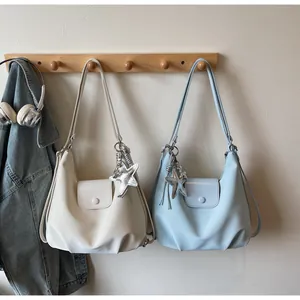 Close-up of stylish half-moon shoulder bags in beige and blue with star pendants