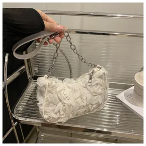 Détail du sac à bandoulière en maille avec roses 3D blanches et bandoulière en chaîne
