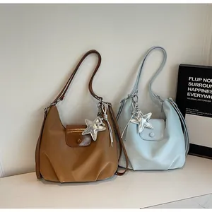 Detail of coffee and blue hobo handbags with star charms and magnetic flap closures