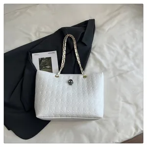 Vue détaillée du motif crâne gaufré blanc et de la bandoulière chaîne sur le sac cabas