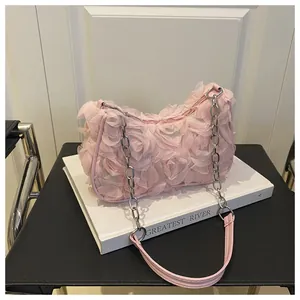 Détail d'un sac à bandoulière rose avec fleurs 3D en textile et chaîne argentée