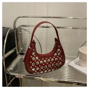 Dettaglio della borsa a mezzaluna rossa con borchie argentate e finitura in vernice lucida