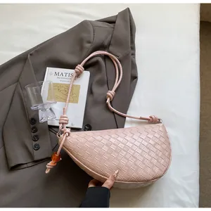 Detalle de bolso de silla en cuero trenzado rosa claro con asa de nudo y abalorio