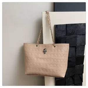 Gros plan détaillé du sac cabas beige avec gaufrage crâne en 3D et ornement métallique chic