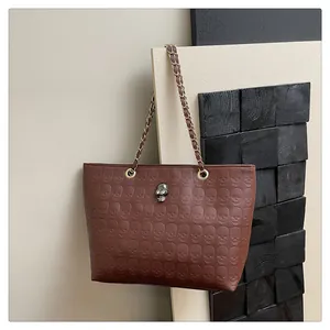 Détail du motif tête de mort en relief sur un sac cabas marron avec breloque métal