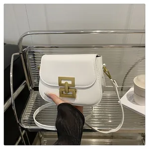 Detailaufnahme der weißen Umhängetasche aus Leder mit goldener Metallschließe und Gurt