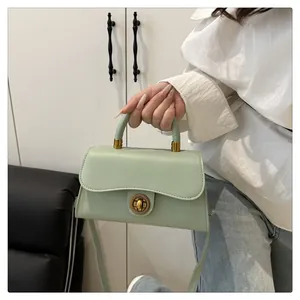 Close-up of mint green vintage handbag featuring a gold circular lock and neat stitching