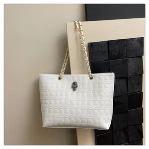 Détail du sac cabas blanc avec motif de crâne en relief et ornement métallique