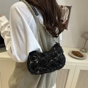 Floral black shoulder bag with 3D rose texture and metallic chain strap worn by a model