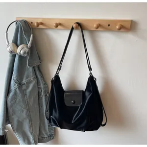 Detail of black glossy Hobo bag with magnetic flap closure hanging on a wooden rack