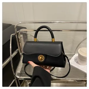Detailed shot of elegant black leather handbag with a golden sunburst twist lock closure